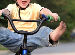 Young boy riding a bike with his feet up